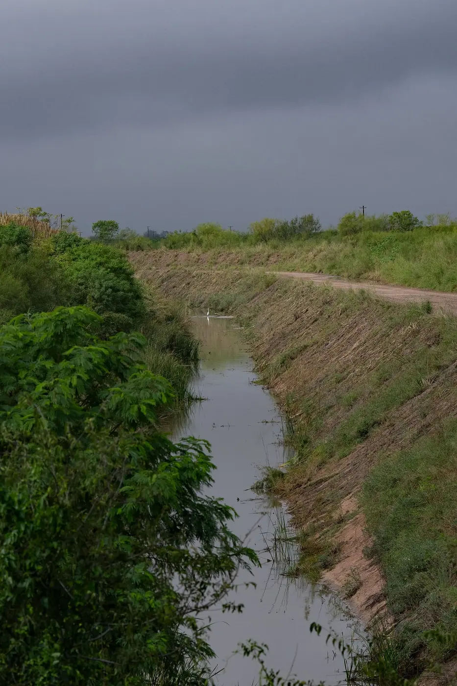 An irrigation canal carrying water alongside farmland
